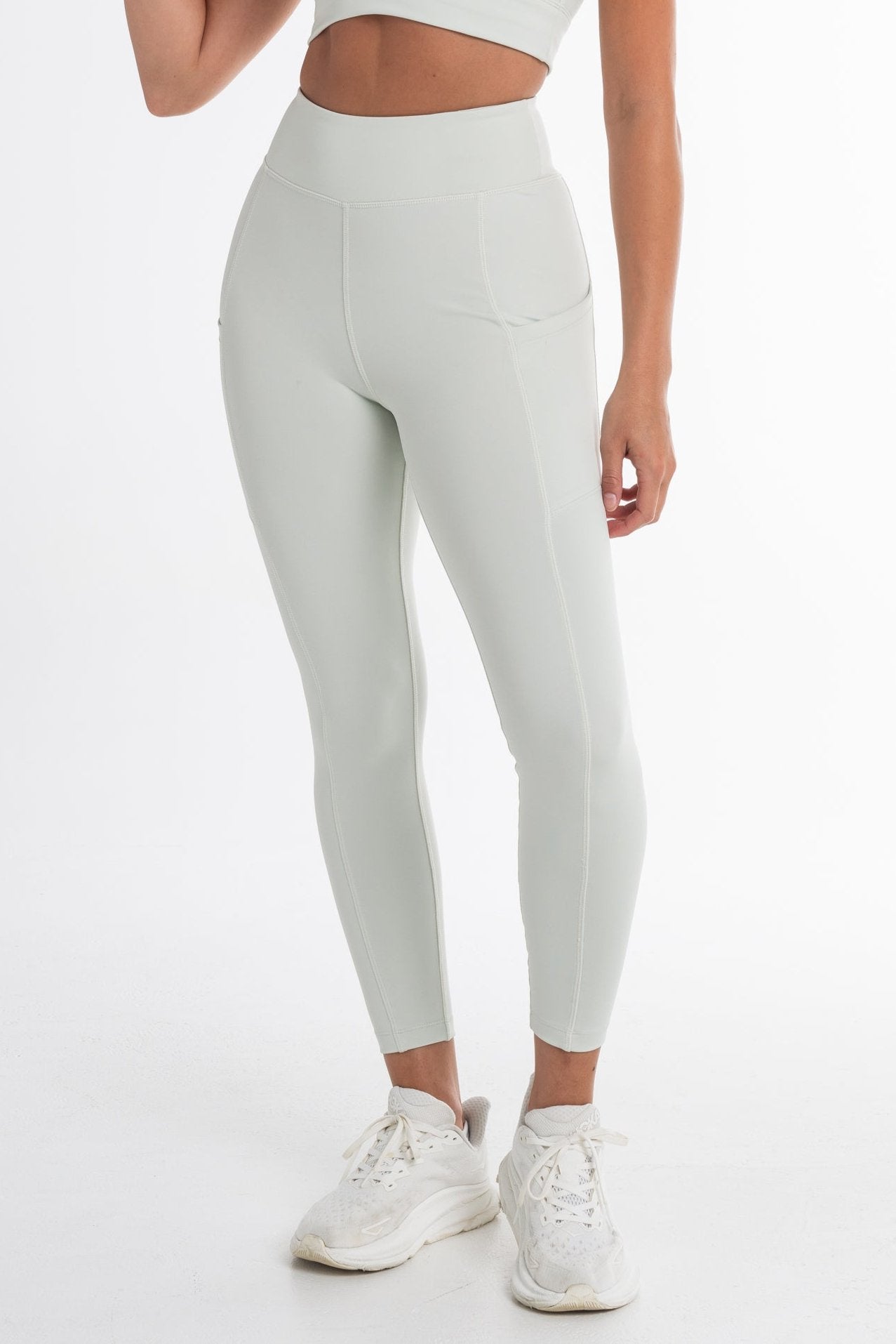 Close-up of a woman wearing a mint ice sports bra and high-waisted leggings, showcasing a sculpted fit with side pockets and a seamless, breathable design. Ideal for active and versatile wear.