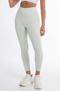 Close-up of a woman wearing a mint ice sports bra and high-waisted leggings, showcasing a sculpted fit with side pockets and a seamless, breathable design. Ideal for active and versatile wear.
